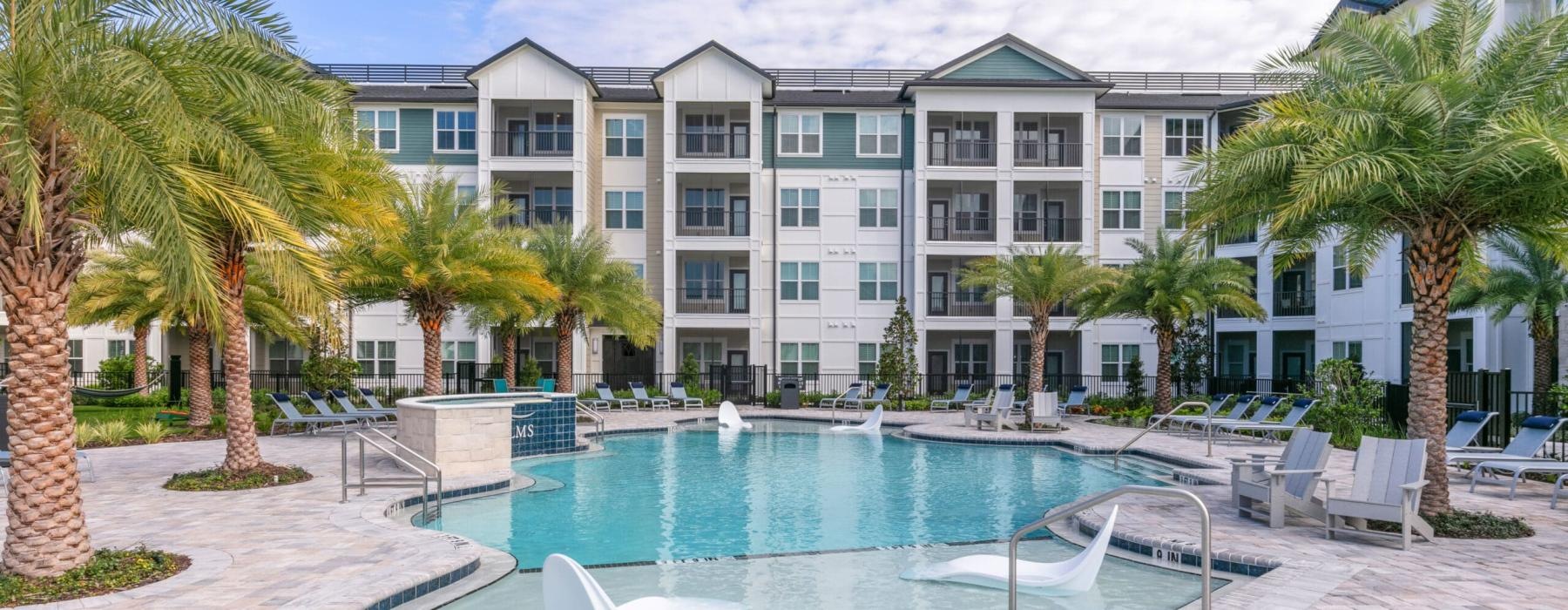 a pool with palm trees in front of a building