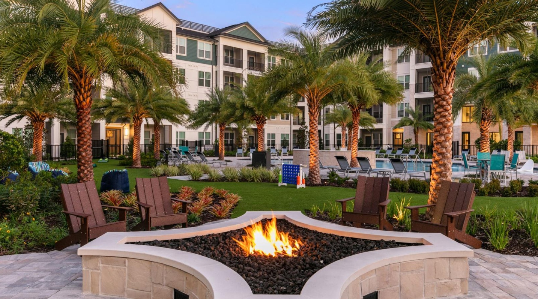 a fire pit with chairs and a fire in front of a building
