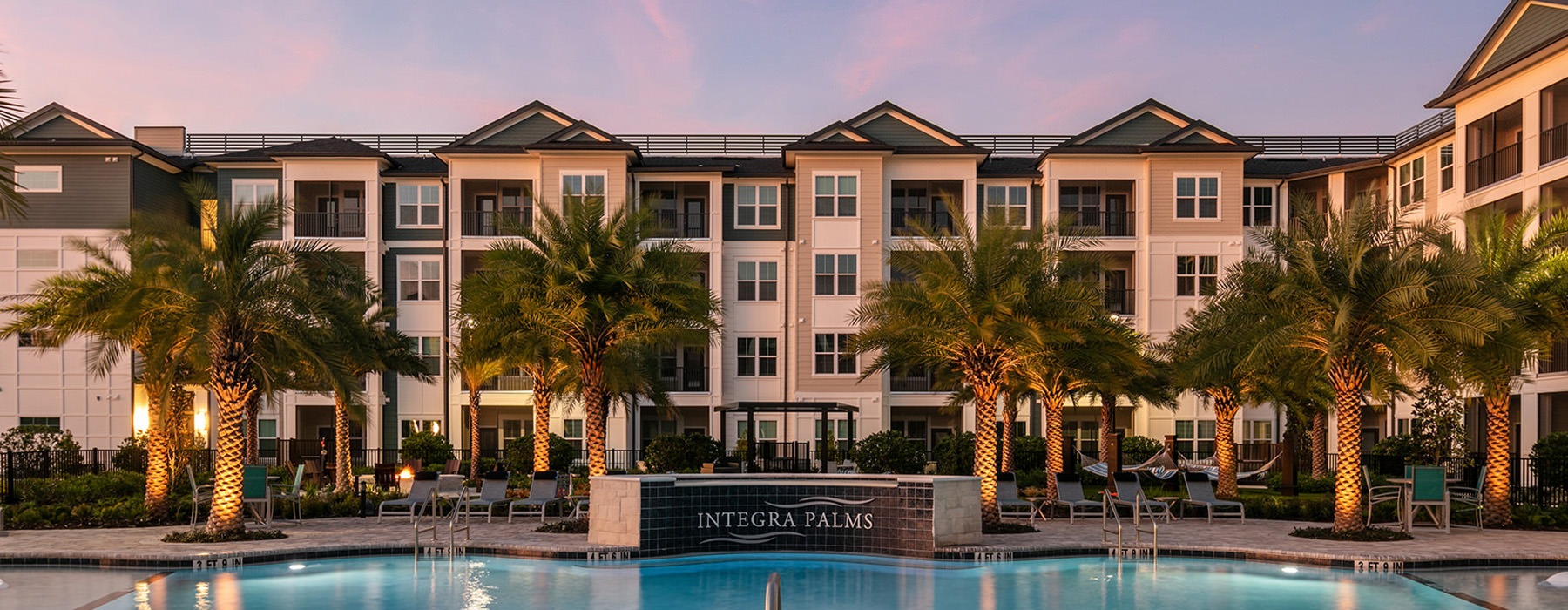 a pool at dusk with a large building behind it